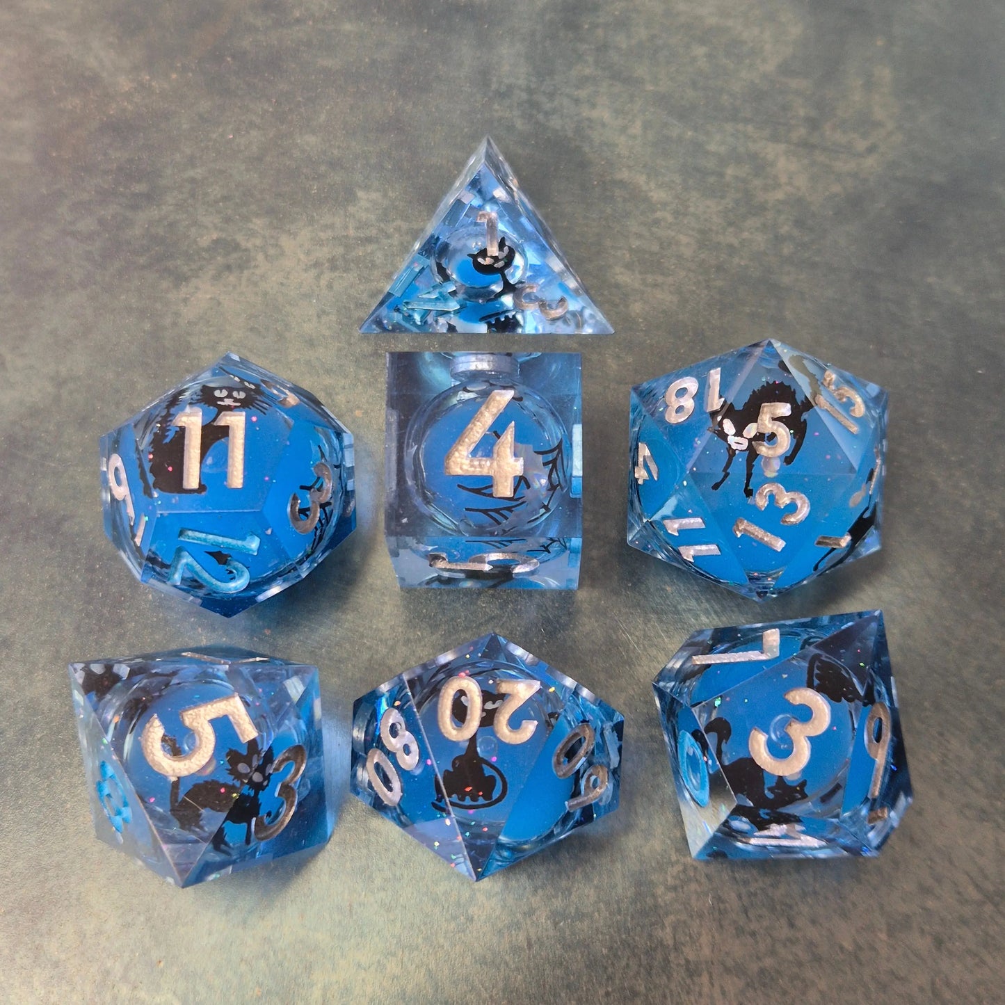 Blue sharp edge resin dice set with liquid core and black cat stickers on metal plate