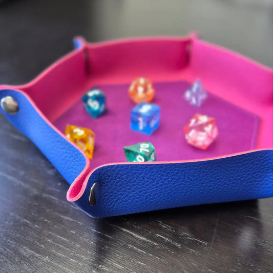 Foldable hexagon-shaped dice trays in pink & purple shown open and filled with colorful polyhedral dice.