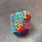 A red and blue translucent D100 dice with gold numbering and iridescent flecks, displayed on a metallic surface.
