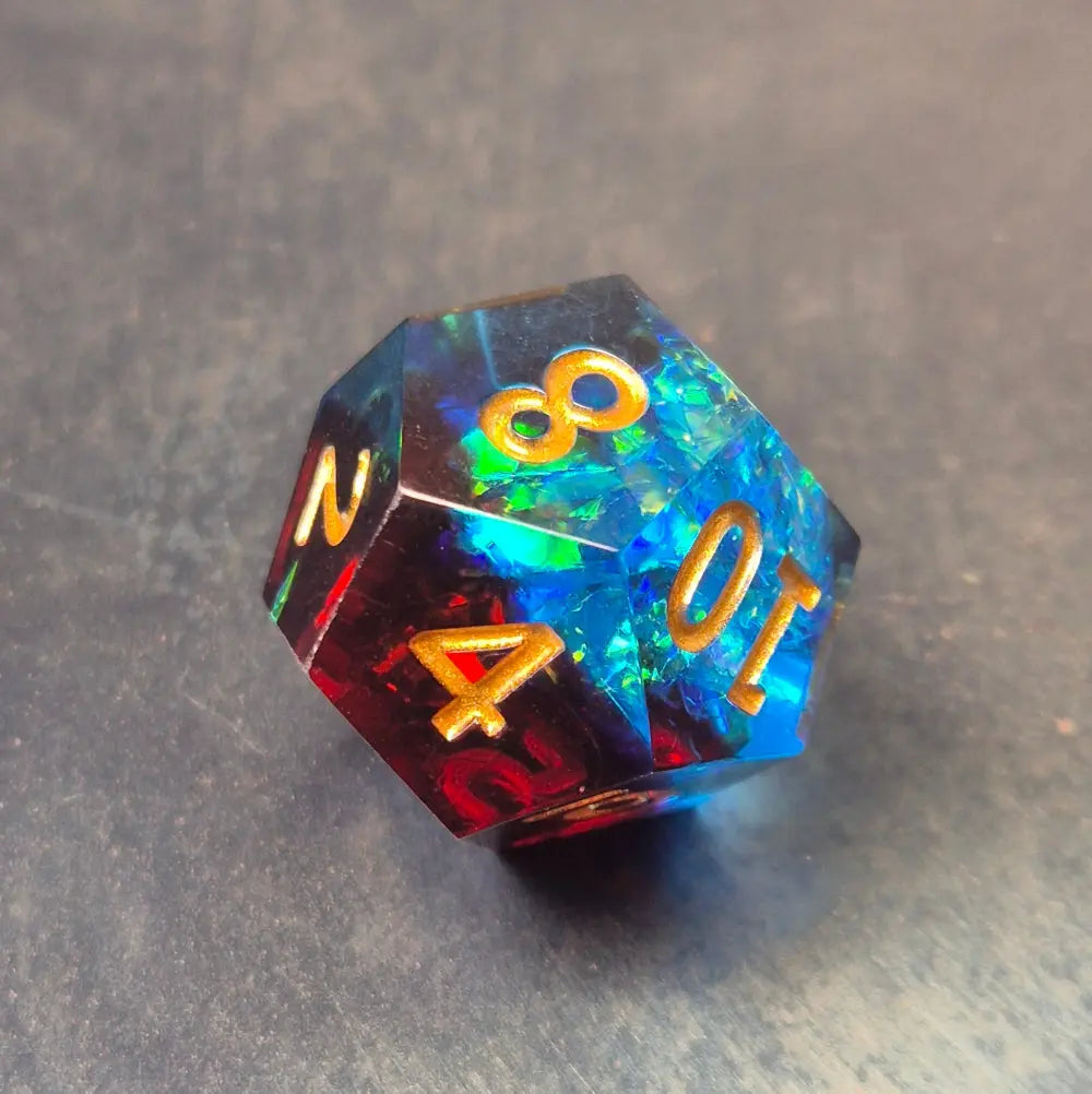 A set of red and blue translucent D12 dice with gold numbering and iridescent flecks, displayed on a metallic surface.