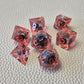 A set of red tinted clear liquid core dice with a moving dragon eye inside on a white textured background
