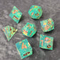 Sharp-edge polyhedral dice set with clear aqua blue resin, filled with holographic foil flakes and copper inked numbers, displayed on a black surface.