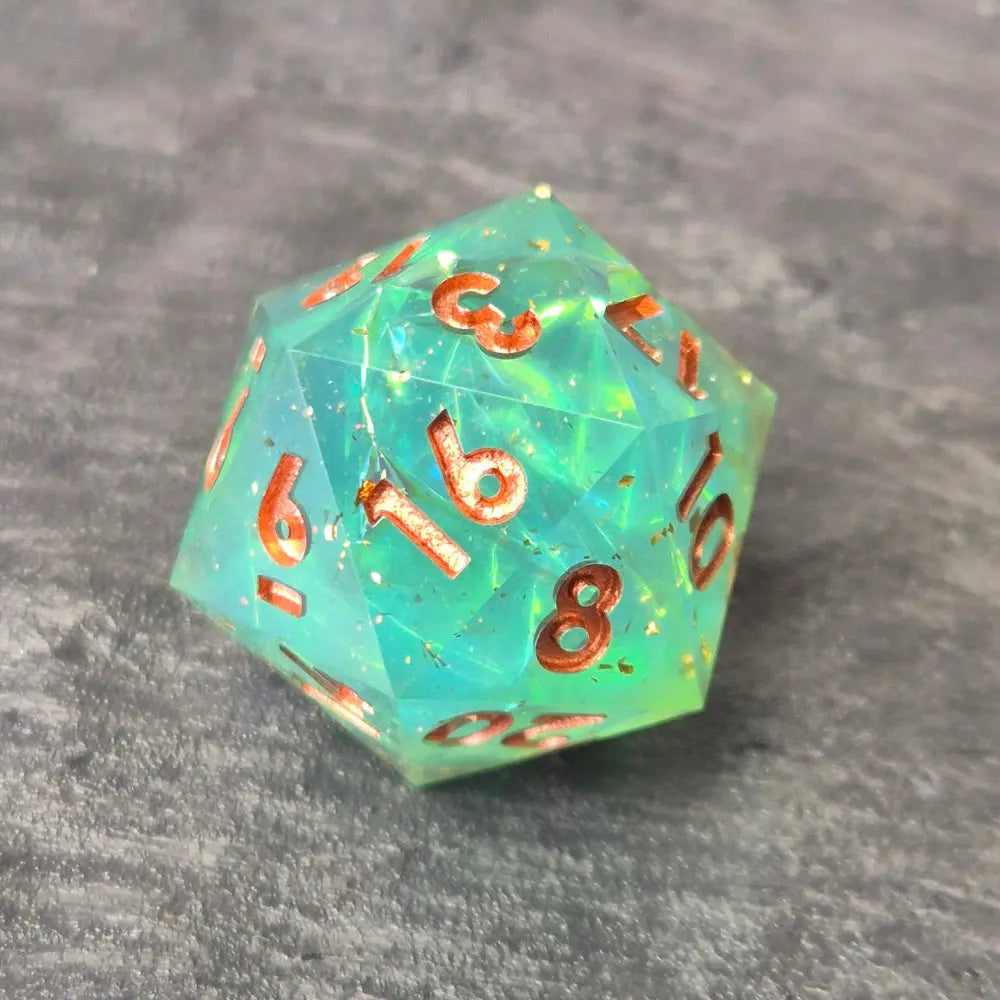 Sharp-edge D20 dice set with clear aqua blue resin, filled with holographic foil flakes and copper inked numbers, displayed on a black surface.