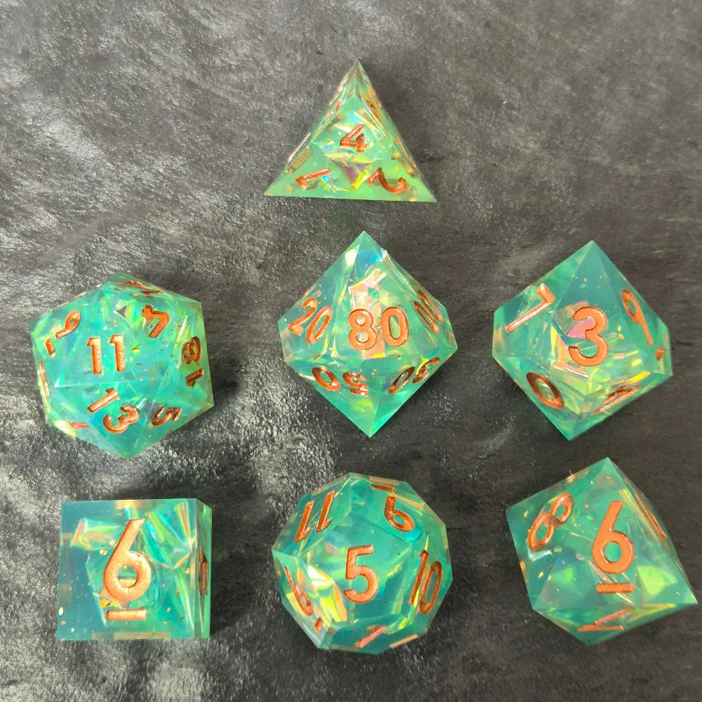 Sharp-edge polyhedral dice set with clear aqua blue resin, filled with holographic foil flakes and copper inked numbers, displayed on a black surface.