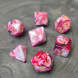 A set of red and white acrylic polymere dice with gold numbers on a wooden surface