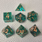 A set of turquoise tinted clear sharp edge resin dice filled with gold flakes. Displayed on a white textured surface