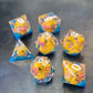 Whimsical sharp-edge dice set with floating yellow ducks and pink numbering, set in clear resin over a blue water-like base.