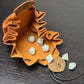 A brown leather dice bag with buttons and rope to tightly close it. Displayed on a black textured background