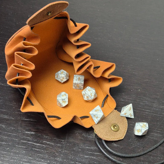 A brown leather dice bag with buttons and rope to tightly close it. Displayed on a black textured background