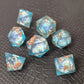 A set of clear light blue tinted liquid core dice with floating bronze flakes and white numbers, displayed on a black textured surface