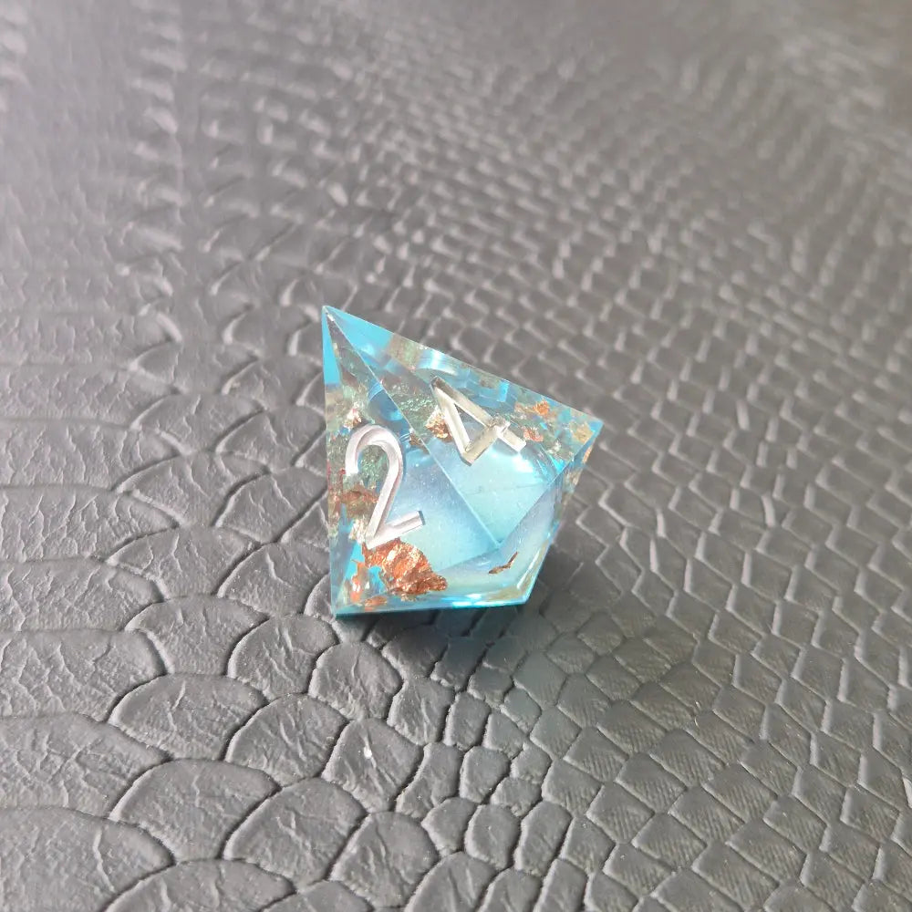 A set of clear light blue tinted liquid core dice with floating bronze flakes and white numbers, displayed on a black textured surface