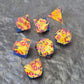 A set of clear sharp-edge resin dice with blue ground color and yellow flower inside on a black surface