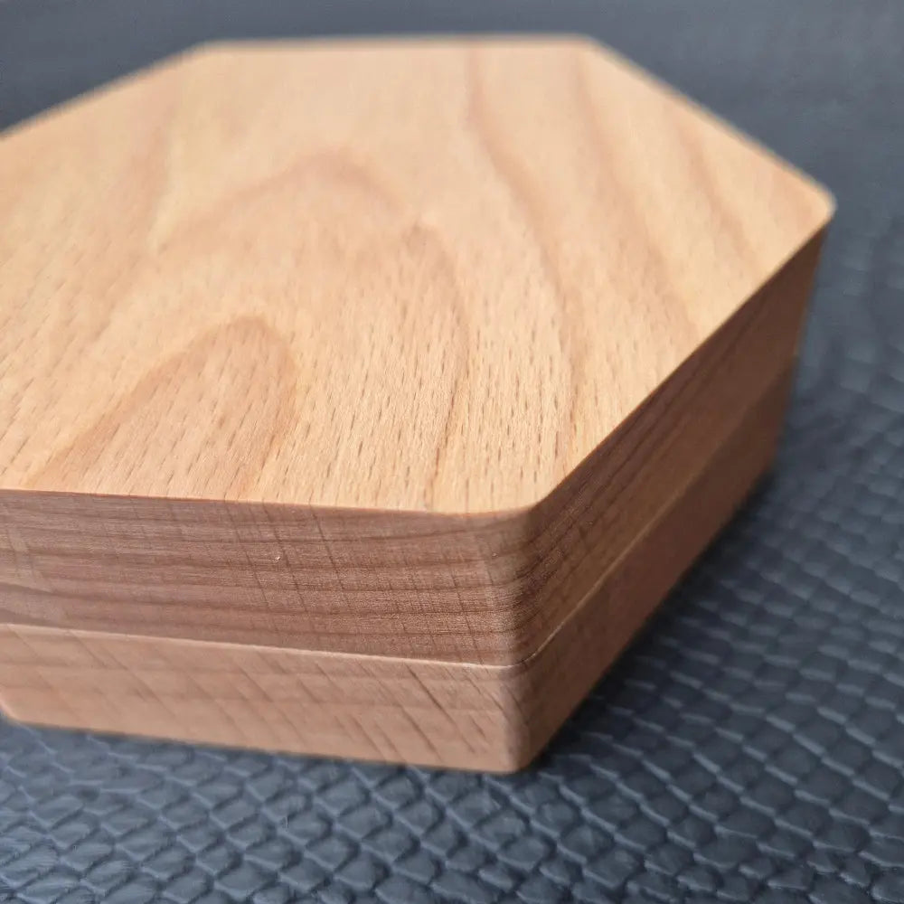 A Wooden Hexagon shaped Dice storage box with magnets on a black textured surface