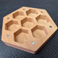A Wooden Hexagon shaped dice storage box with magnets on a black textured surface