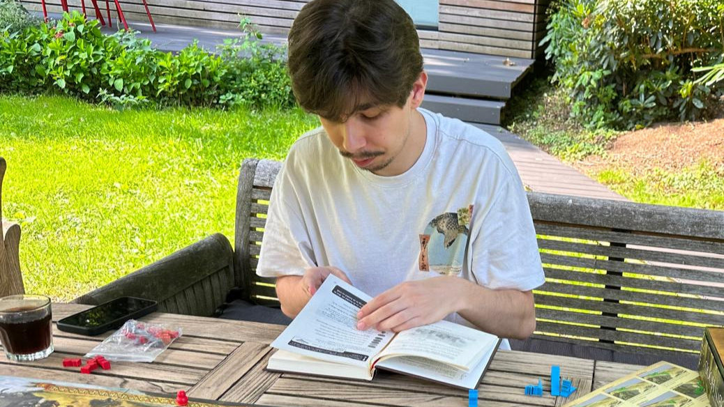 Person playing a board game outdoors with snacks and drinks on a table