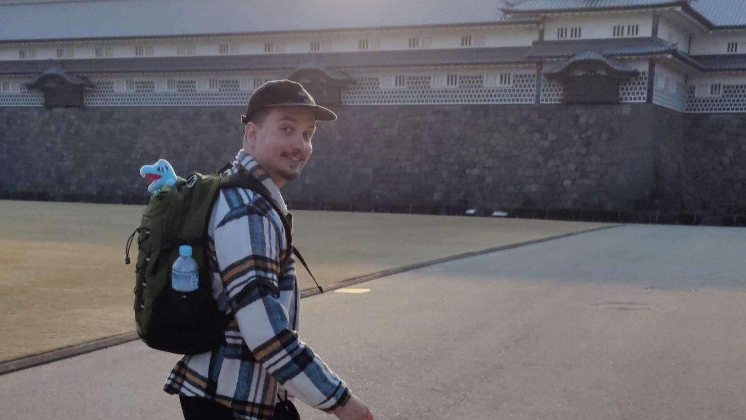 Man walking on a paved area with a building in the background