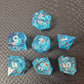 A set of clear light blue tinted liquid core dice with koi fish and glitters inside, displayed on a black textured surface