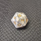 D20 white marble-textured gemstone die with gold numbering, displayed on a black leather surface.