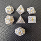 Set of white marble-textured gemstone dice with gold numbering, displayed on a black leather surface.