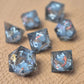 A set of clear grey tinted liquid core resin dice with koi fish inside filled with glitters on a beige textured surface