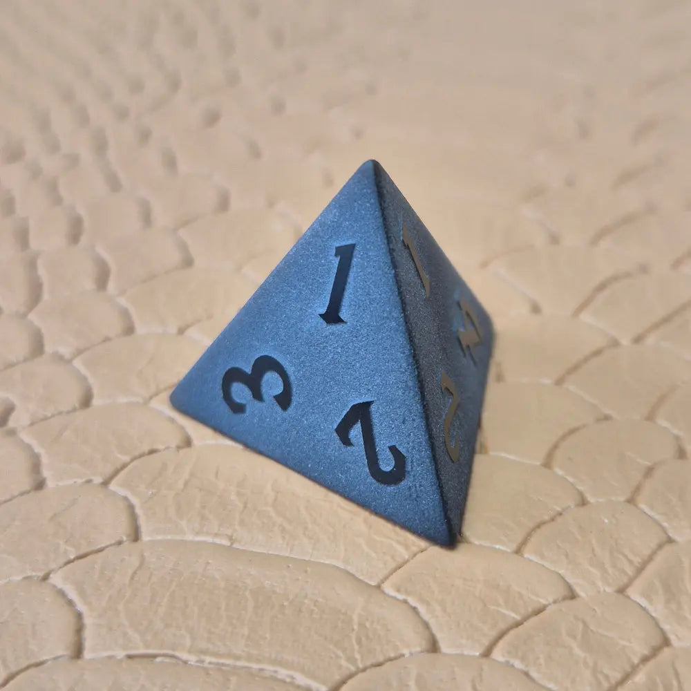 A set of matte black/ dark grey gemstone dice on a beige textured surface