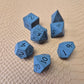 A set of matte black/ dark grey gemstone dice on a beige textured surface