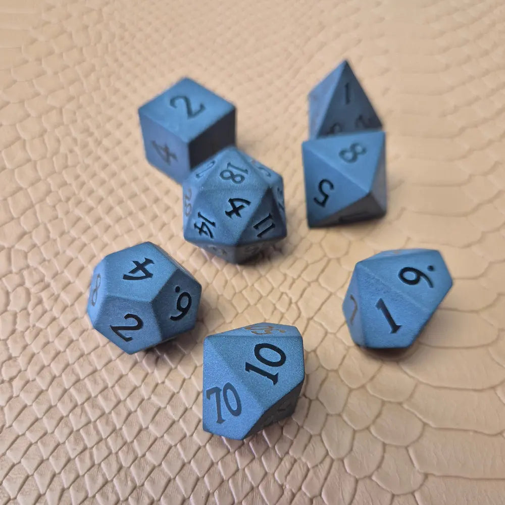 A set of matte black/ dark grey gemstone dice on a beige textured surface