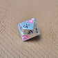 A set of silver metal dice with pink flowers and green stems and black numbers engraved, on a beige textured surface