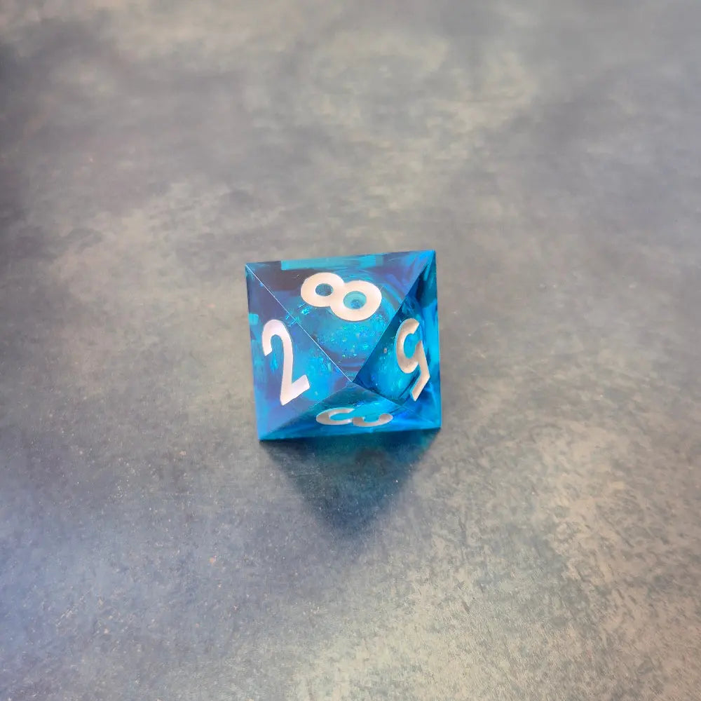 A set of rainbow coloured resin dice witch liquid core displayed on metal plate