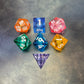 A set of rainbow coloured resin dice witch liquid core displayed on metal plate