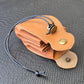 A brown leather dice bag with buttons and rope to tightly close it. Displayed on a black textured background