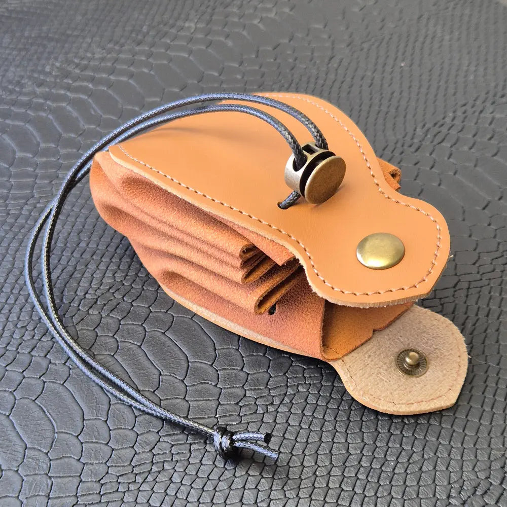A brown leather dice bag with buttons and rope to tightly close it. Displayed on a black textured background