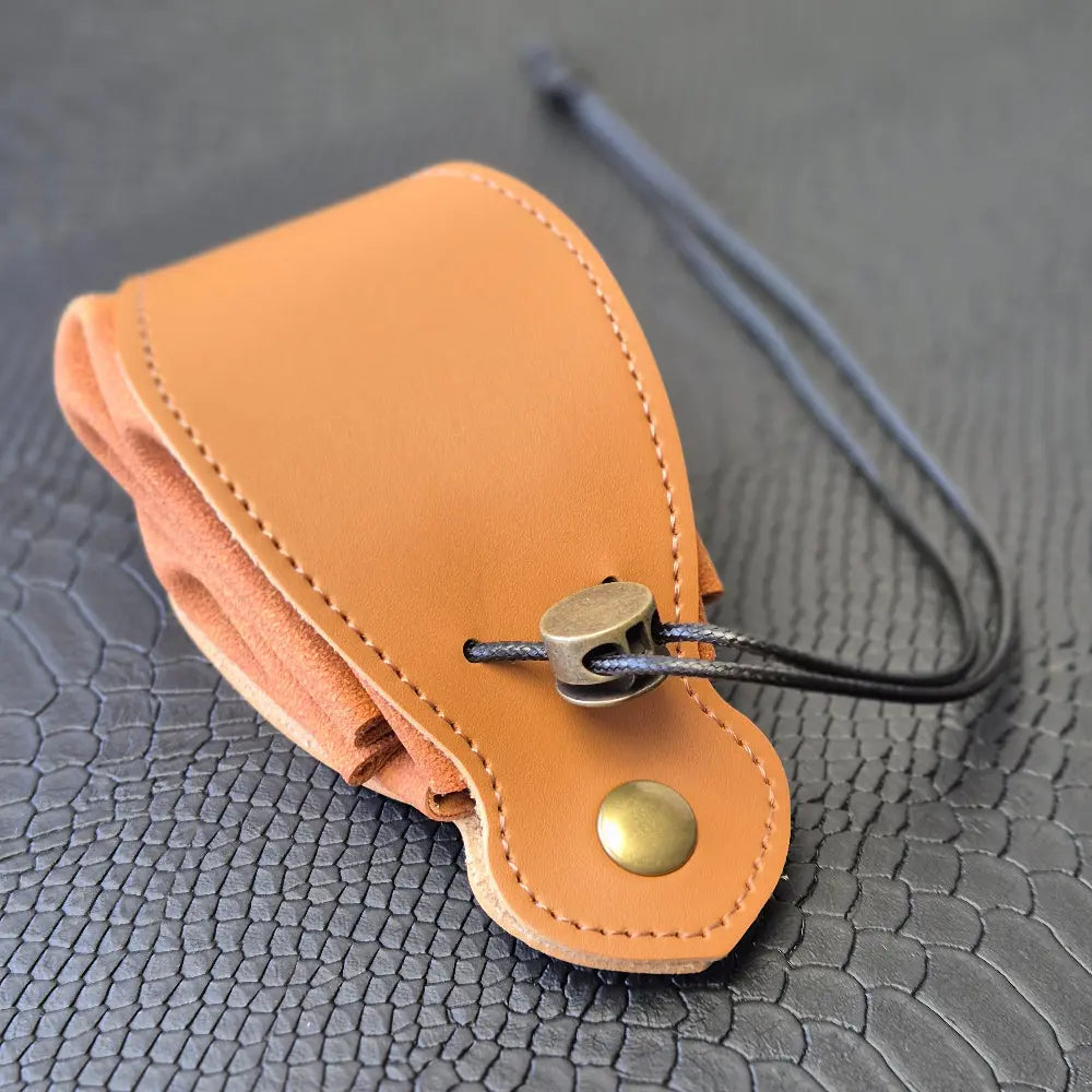 A brown leather dice bag with buttons and rope to tightly close it. Displayed on a black textured background