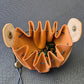 A brown leather dice bag with buttons and rope to tightly close it. Displayed on a black textured background