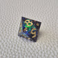 A set of blue sharp edge resin dice with green confetti inside on a white textured surface
