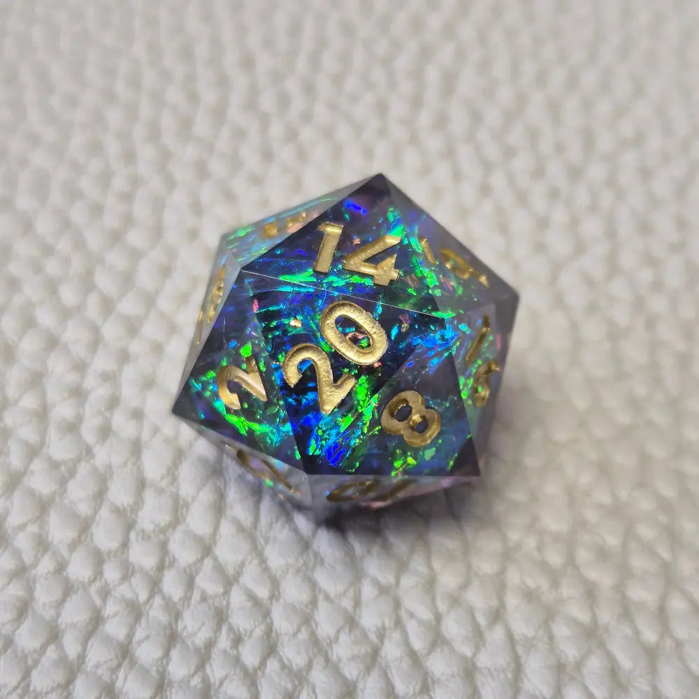 A set of blue sharp edge resin dice with green confetti inside on a white textured surface
