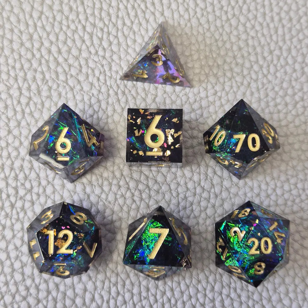 A set of blue sharp edge resin dice with green confetti inside on a white textured surface