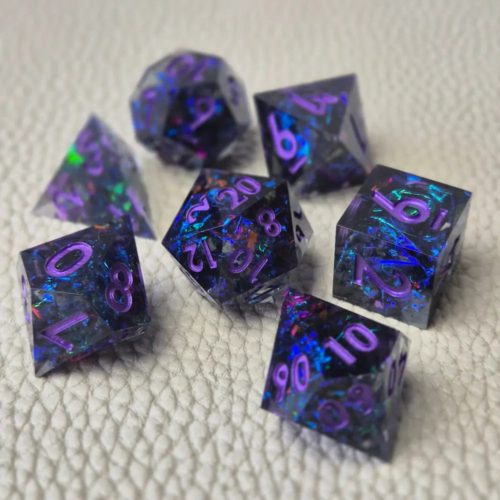 A set of purple sharp edge resin dice with blue confetti inside on a white textured surface