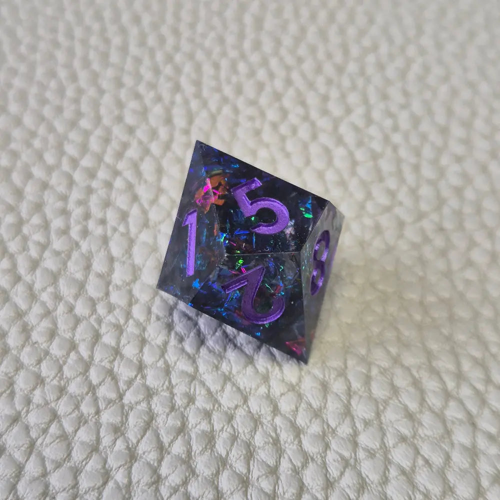 A set of purple sharp edge resin dice with blue confetti inside on a white textured surface