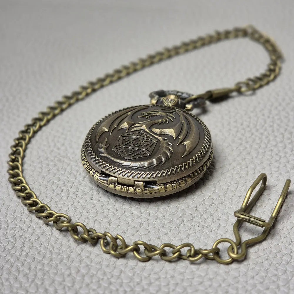 A Bronze coloured full metal pocket watch themed dice locket, with engraved backside and detailed dragon on the front. Contains full set of metal dice inside