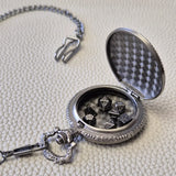 A silver coloured full metal pocket watch themed dice locket, with engraved backside and detailed dragon on the front. Contains full set of metal dice inside