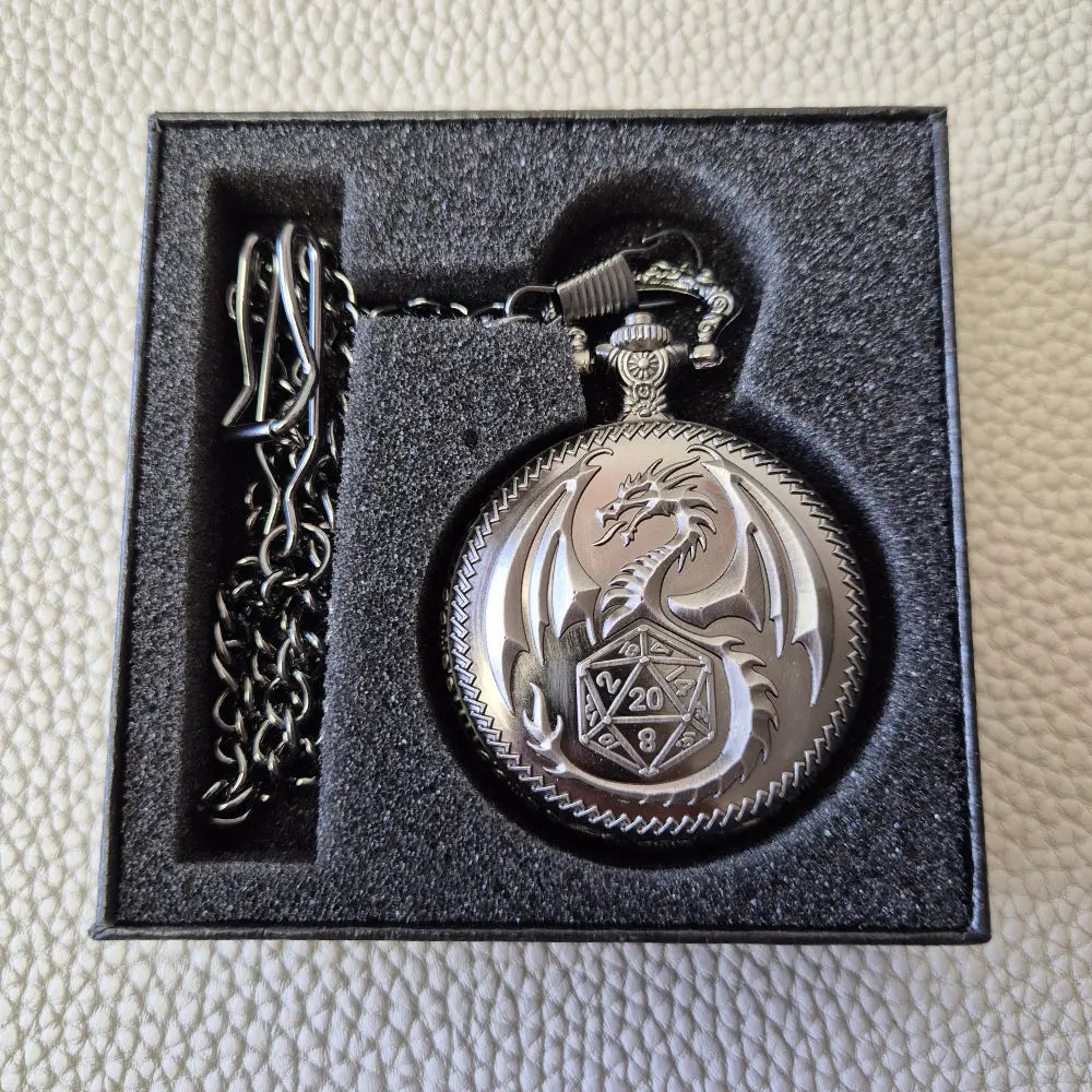 A silver coloured full metal pocket watch themed dice locket, with engraved backside and detailed dragon on the front. Contains full set of metal dice inside