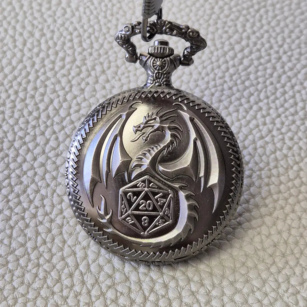 A silver coloured full metal pocket watch themed dice locket, with engraved backside and detailed dragon on the front. Contains full set of metal dice inside