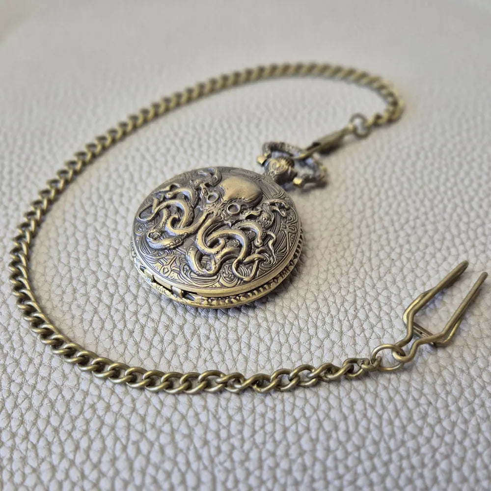 A Bronze coloured full metal pocket watch themed dice locket, with engraved backside and detailed kraken on the front. Contains full set of metal dice inside