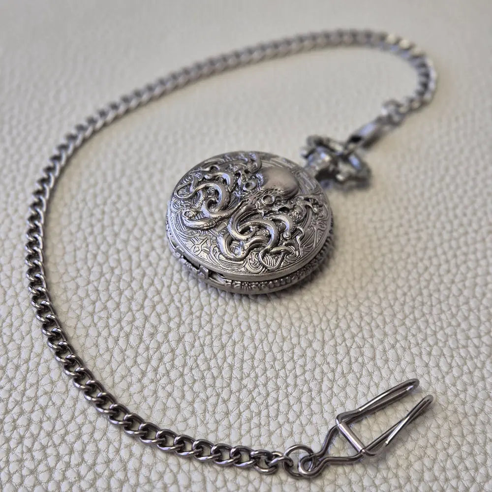 A silver coloured full metal pocket watch themed dice locket, with engraved backside and detailed kraken on the front. Contains full set of metal dice inside