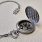A silver coloured full metal pocket watch themed dice locket, with engraved backside and detailed kraken on the front. Contains full set of metal dice inside