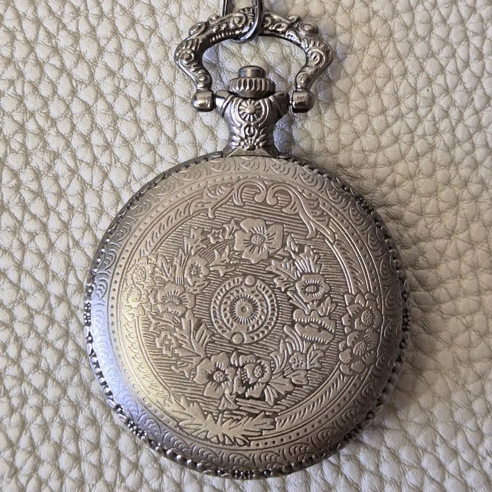 A silver coloured full metal pocket watch themed dice locket, with engraved backside and detailed kraken on the front. Contains full set of metal dice inside