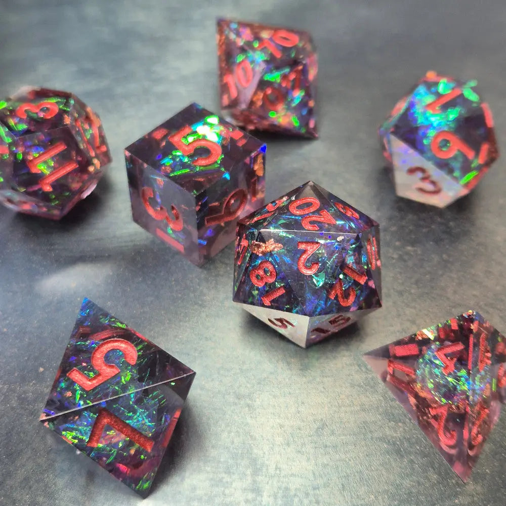 A set of clear purple tinted sharp edge resin dice with colourfull confetti inside on a blue metal surface