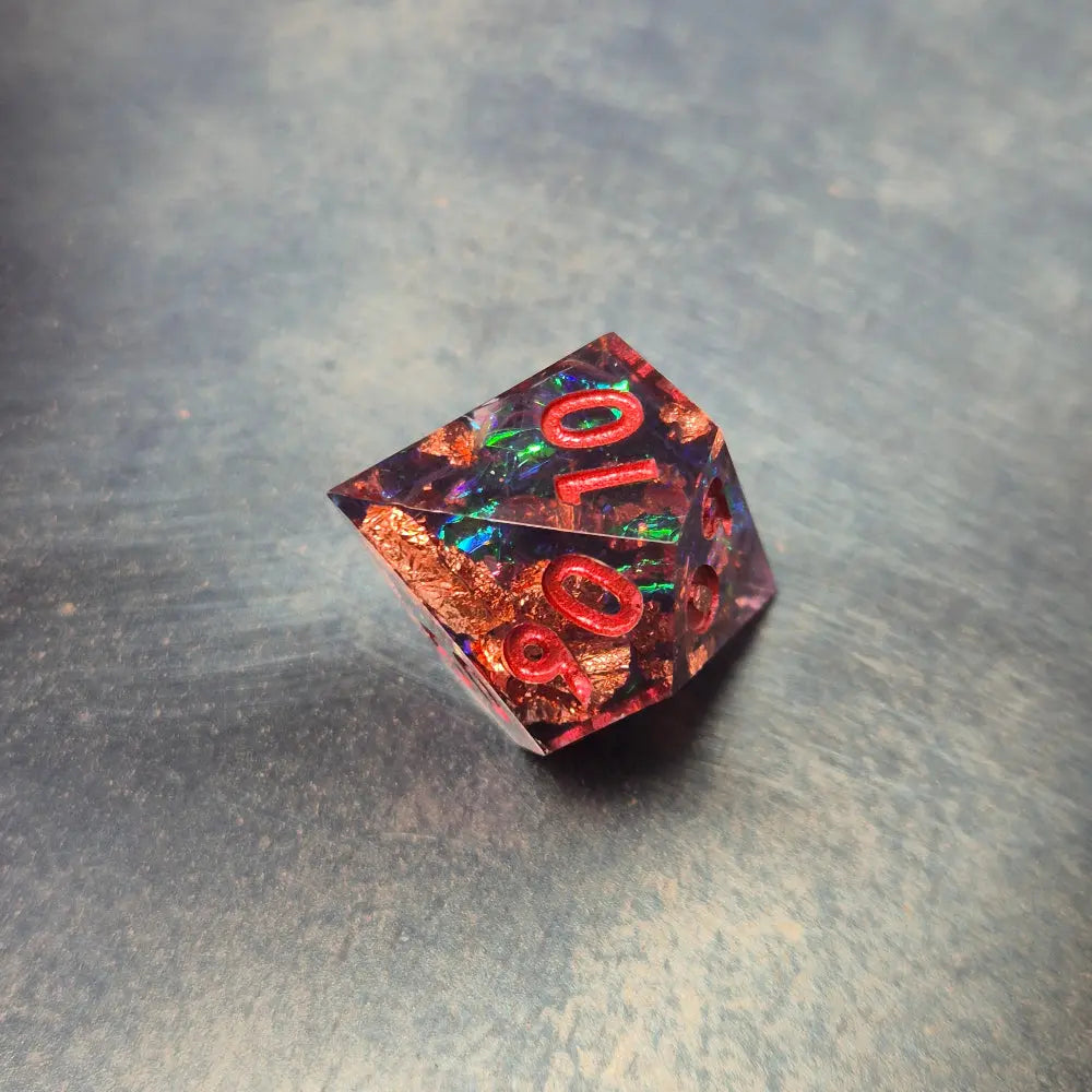 A set of clear purple tinted sharp edge resin dice with colourfull confetti inside on a blue metal surface