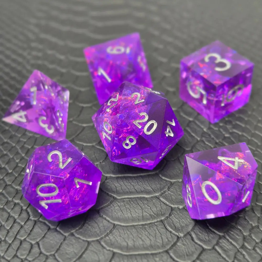 A set of sharp-edge purple resin dice and silver numbering, displayed on a black scale-textured surface.